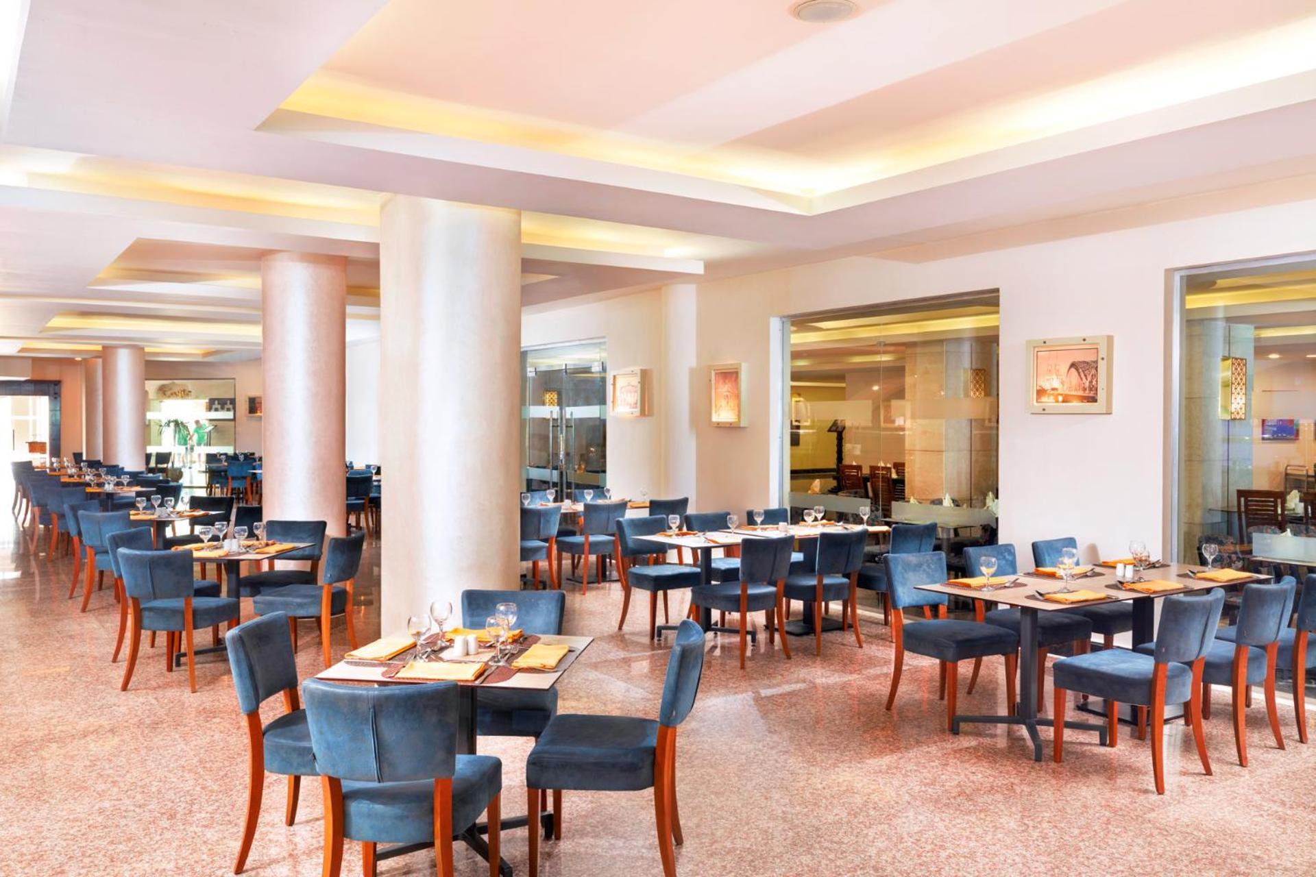 Hotel Pickalbatros Royal Moderna Sharm "Aqua Park" Esterno foto The photo shows a spacious restaurant interior. It features several sets of tables and chairs arranged in a well-organized manner. The tables are dressed with placemats and utensils, indicating they are prepared for dining. The color scheme includes 
